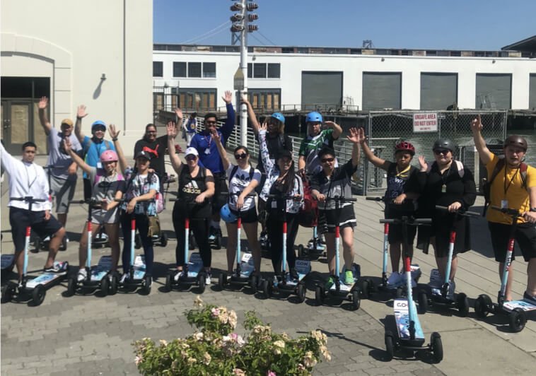 A large group of guests lined up with Go X scooters